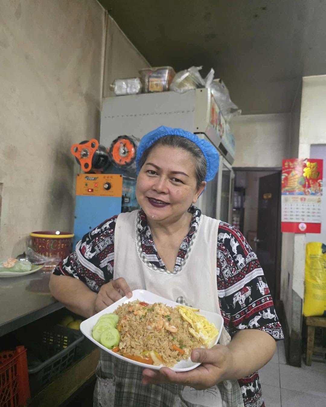 Chef Mommy Ancharee holding a plate of Thai Fried Rice in the Phad Thai Pacita kitchen